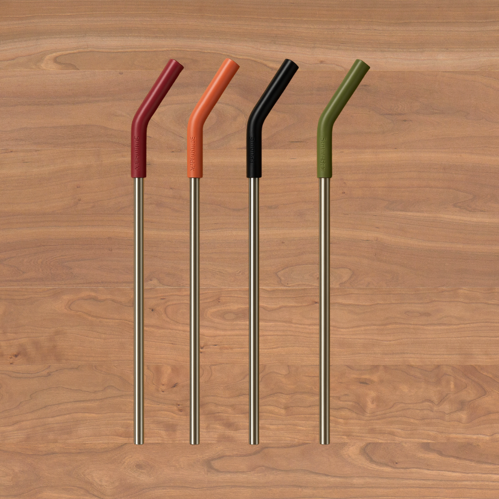 Four colorful antimicrobial straws with bent tips on a wooden surface